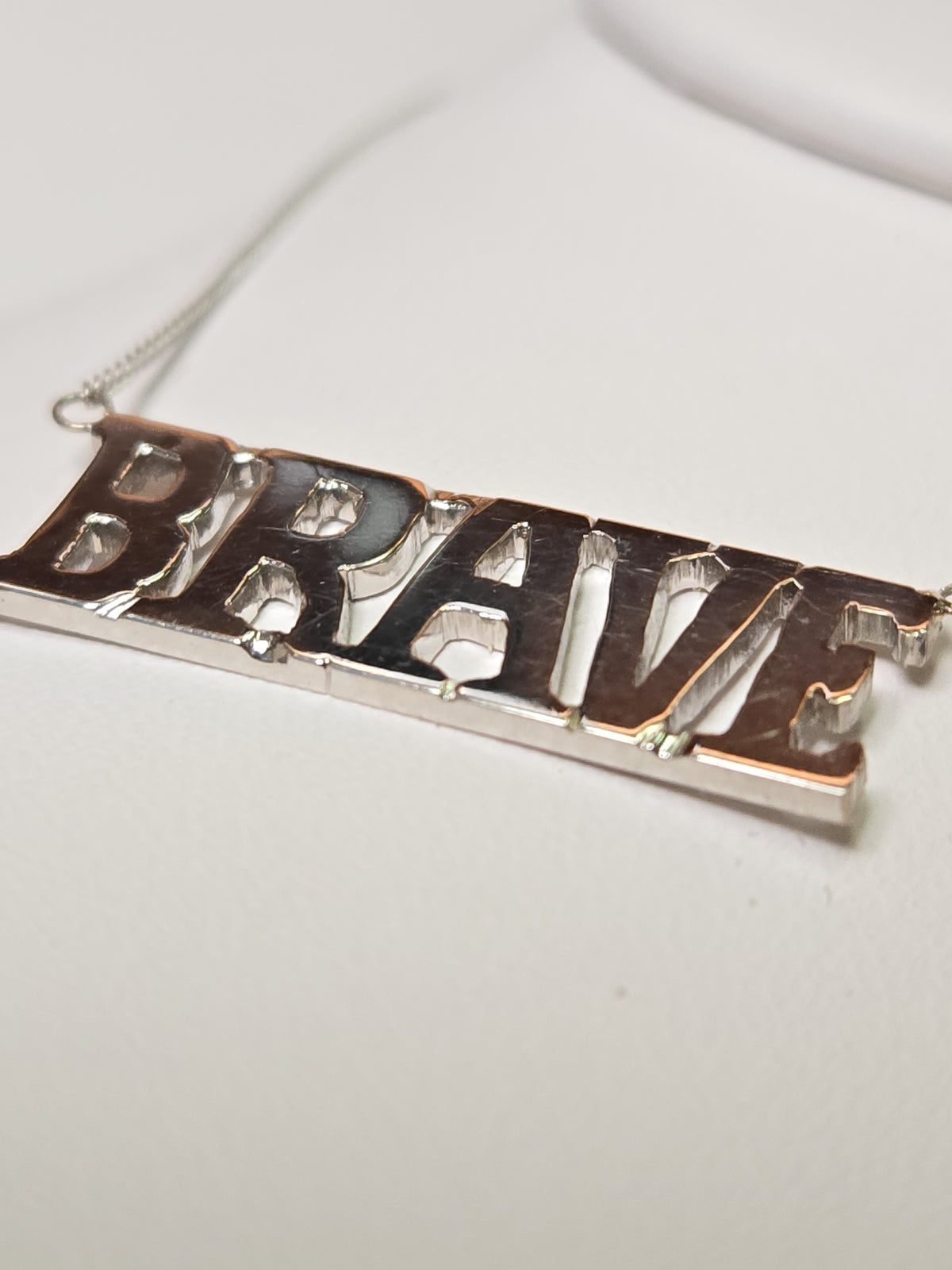 14K white gold diamond cut curb chain necklace with "Brave" pendant, 19-inch length, 3.2 grams from Chique Jewelry.