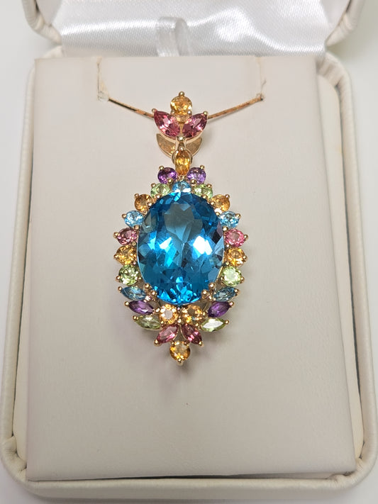 14K gold oval blue topaz pendant from Chique Jewelry showcasing a sparkling blue gemstone on a gold chain.