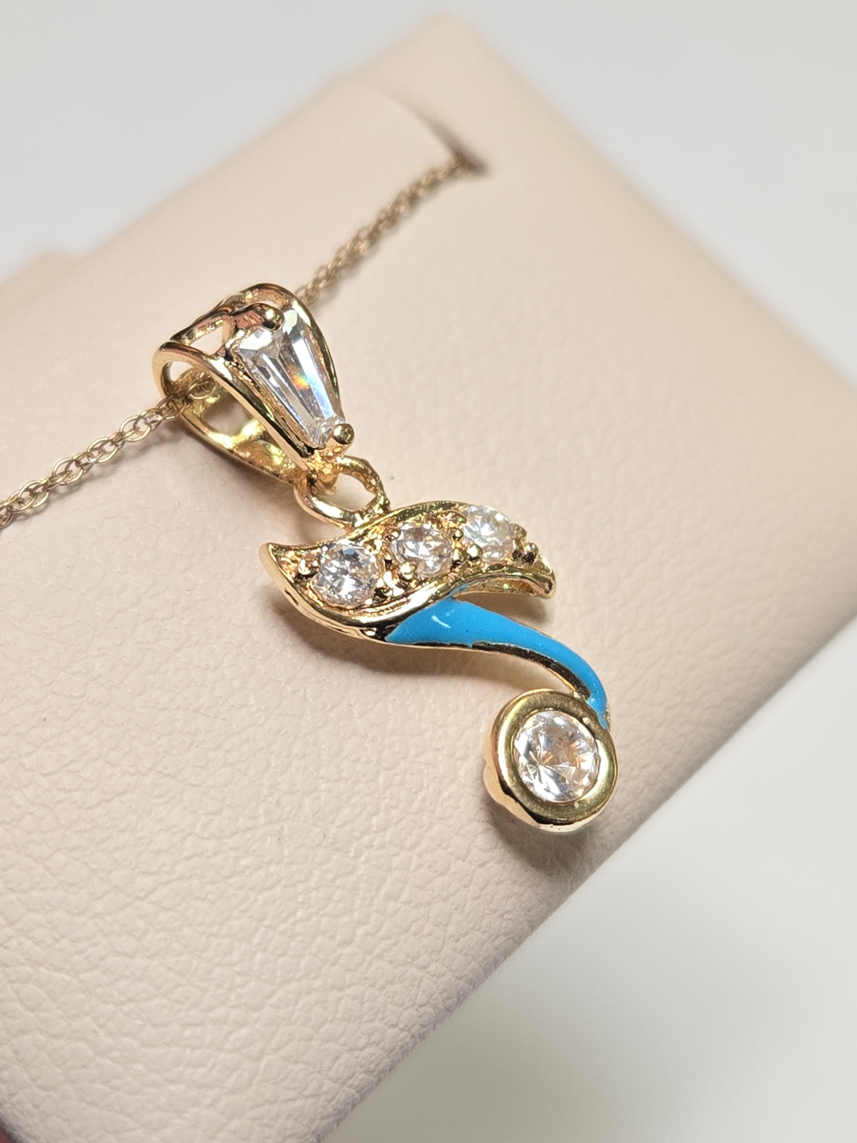 18K gold pendant with cubic zirconias from Chique Jewelry, showcasing a sparkling jewelry piece on a neutral background.