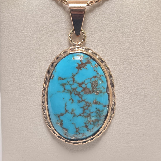 Oval turquoise 10K gold pendant from Chique Jewelry, showcasing a polished gemstone set in a sleek gold pendant.