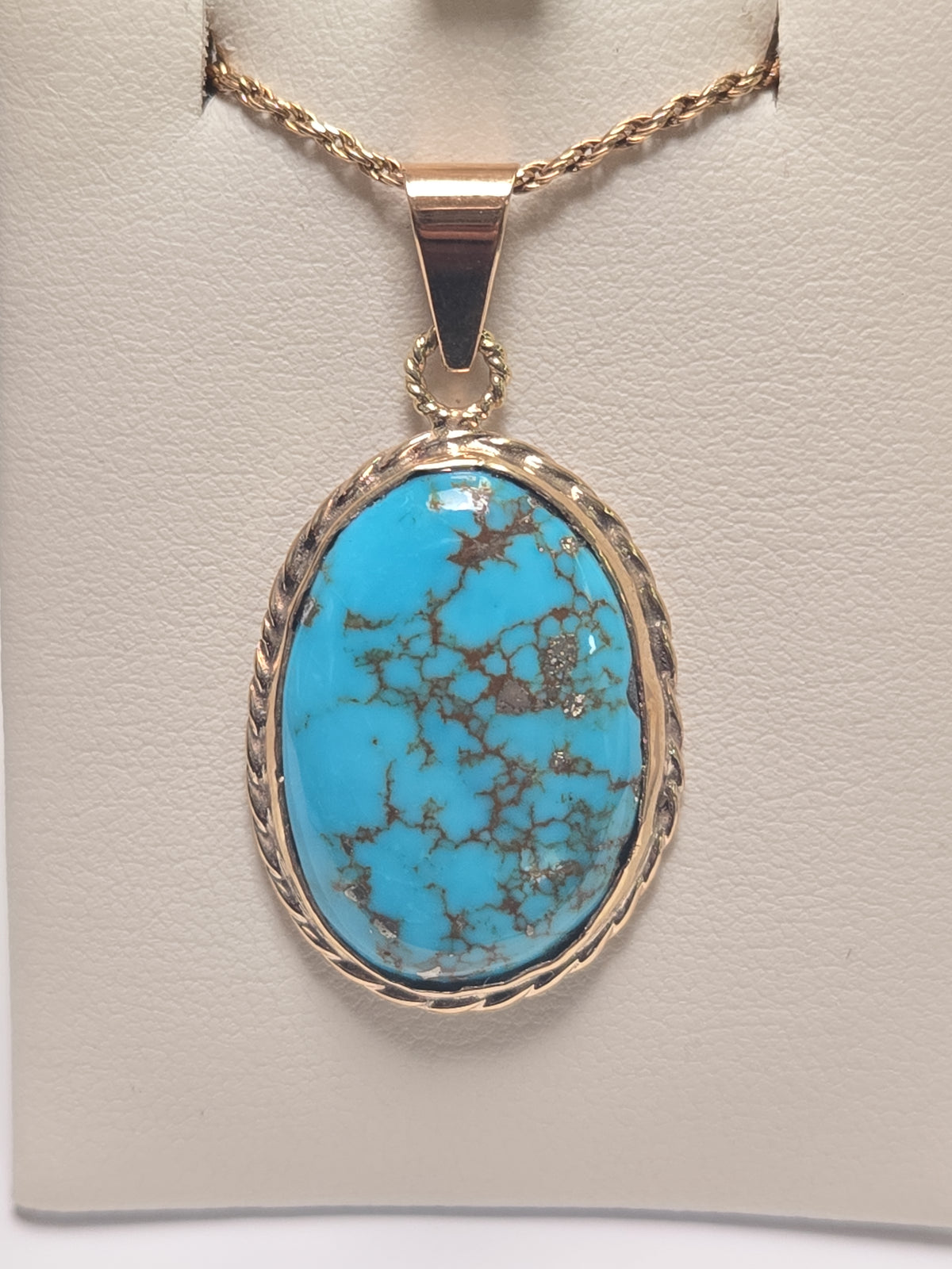 Oval turquoise 10K gold pendant from Chique Jewelry, showcasing a polished gemstone set in a sleek gold pendant.
