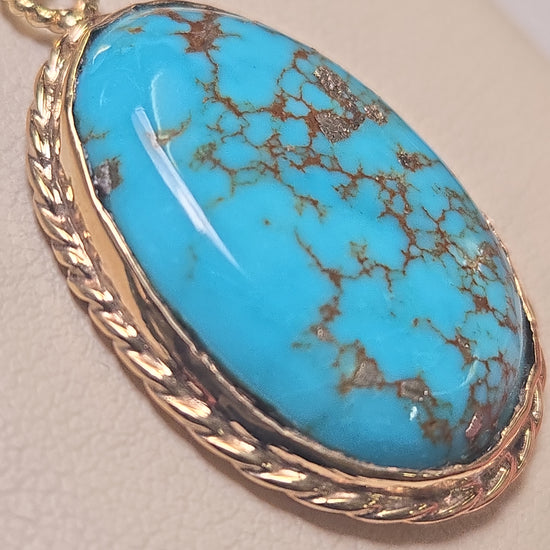 Oval turquoise pendant in 10K gold from Chique Jewelry, showcasing a polished, elegant design with a smooth finish.