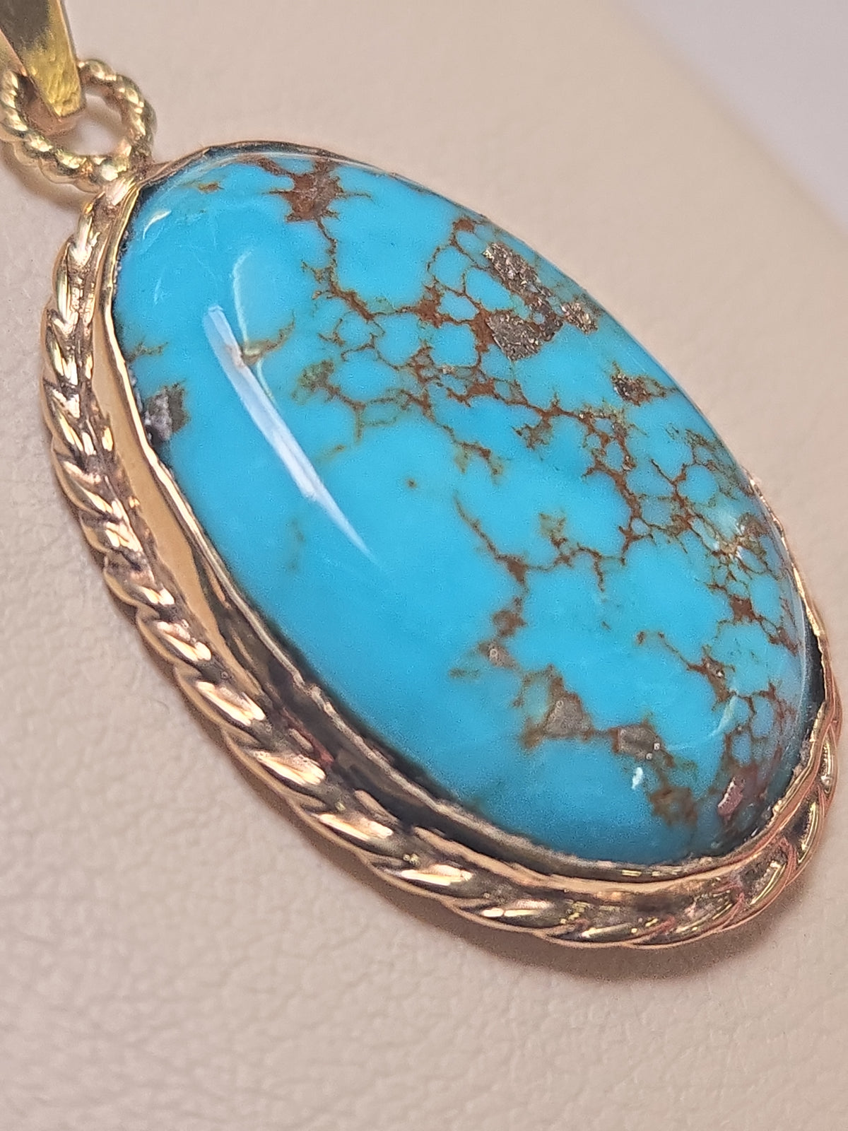 Oval turquoise pendant in 10K gold from Chique Jewelry, showcasing a polished, elegant design with a smooth finish.