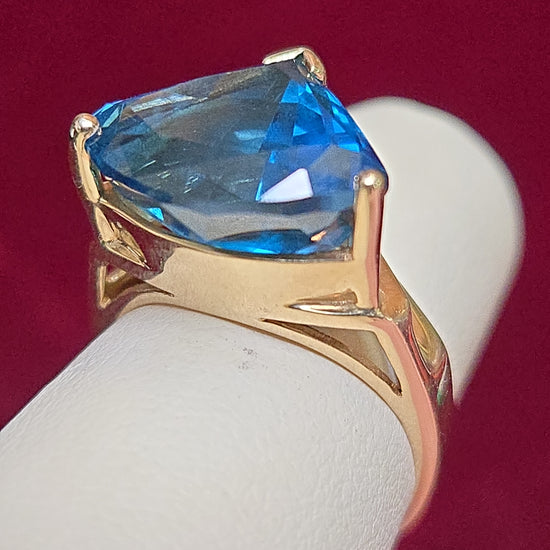 14K gold-colored stone ring featuring a trillion-shaped blue topaz, accented with elegant design details.
