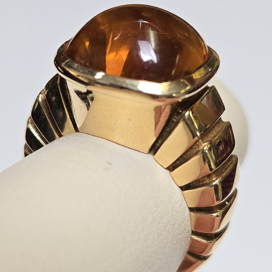 Van Cleef 18K gold ring with a cabochon citrine gemstone, showcasing elegant jewelry design and craftsmanship.