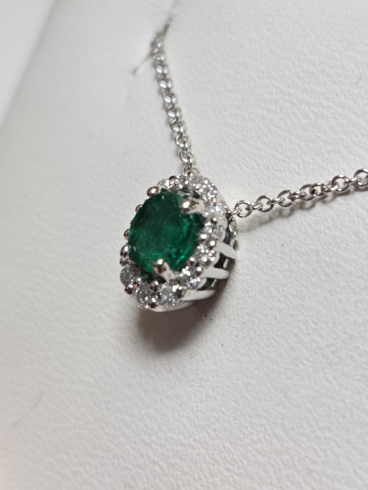 14K white gold pendant featuring a 0.4ct oval emerald, crafted by Chique Jewelry, with delicate detailing and elegant design.