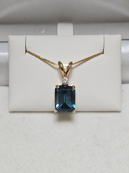 14K gold pendant with 2.88ct emerald-cut blue topaz, featuring a sleek design and polished finish.
