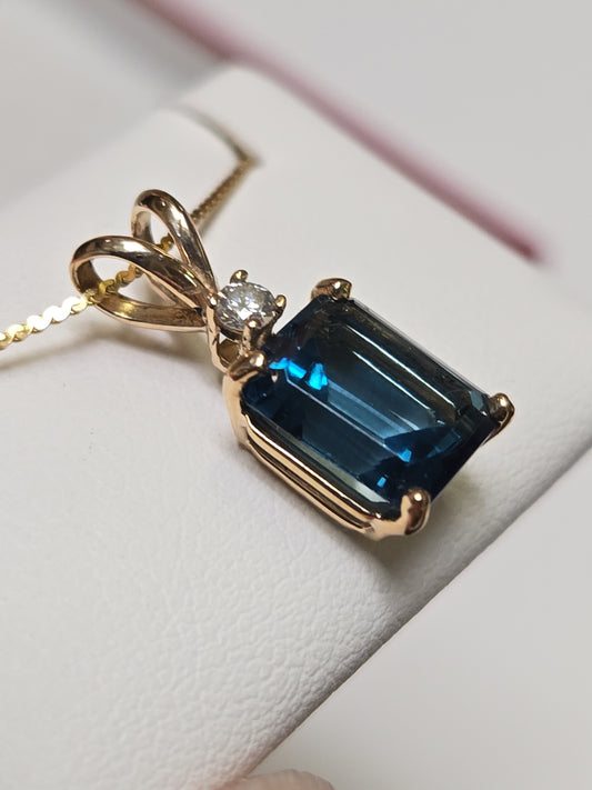 14K gold pendant with a 2.88ct emerald-cut blue topaz, featuring a sleek design and delicate chain by Chique Jewelry.