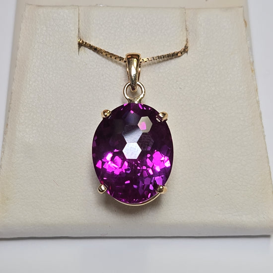 Oval 22ct lab-created alexandrite pendant in 10K gold, elegant jewelry piece with detailed design and vibrant gemstone.