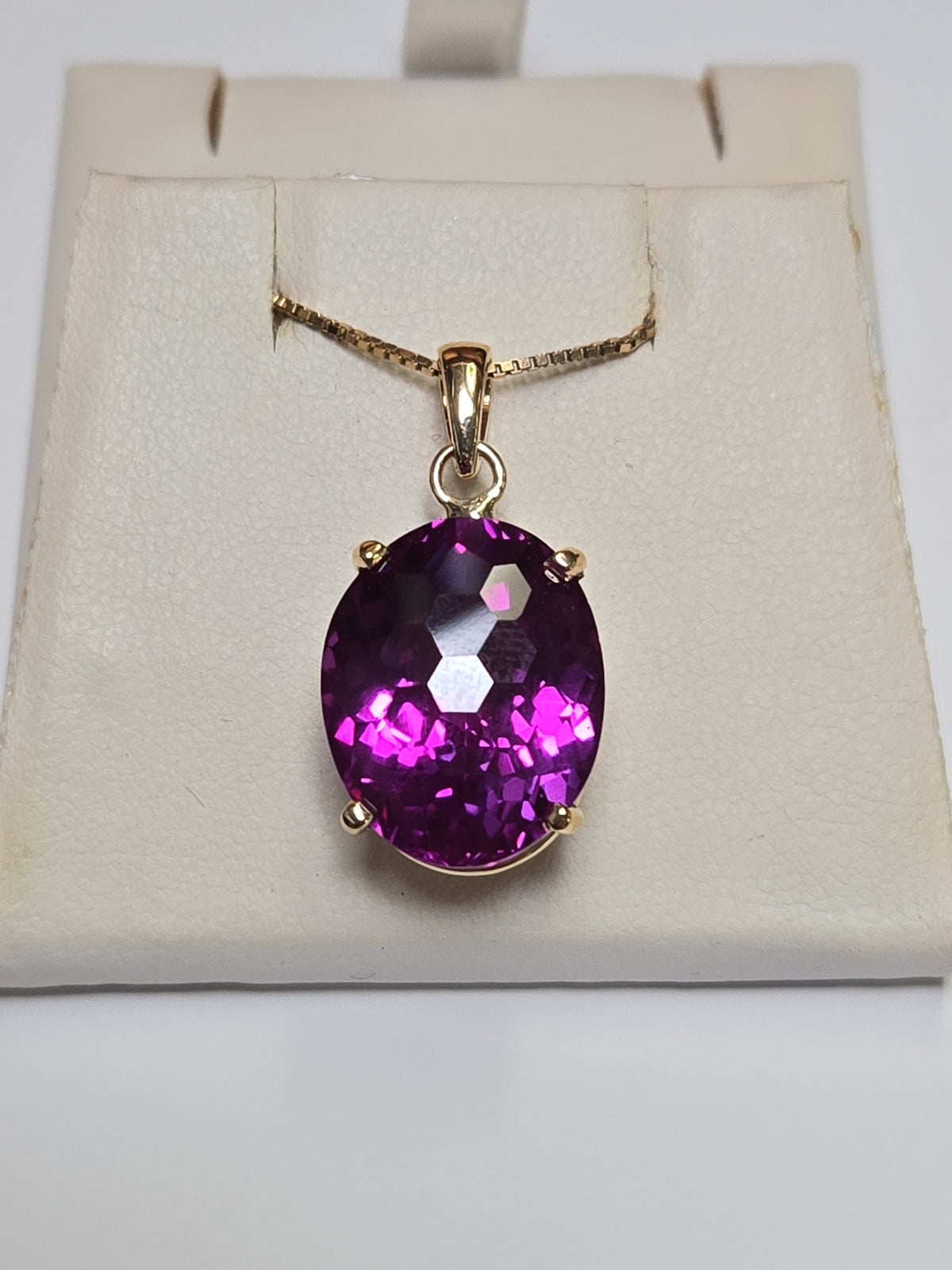 Oval 22ct lab-created alexandrite pendant in 10K gold, elegant jewelry piece with detailed design and vibrant gemstone.