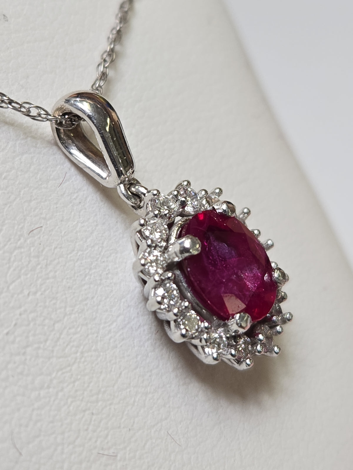 14K white gold pendant with 1.5ct oval ruby, featuring a delicate design and weighing 2.7 grams.