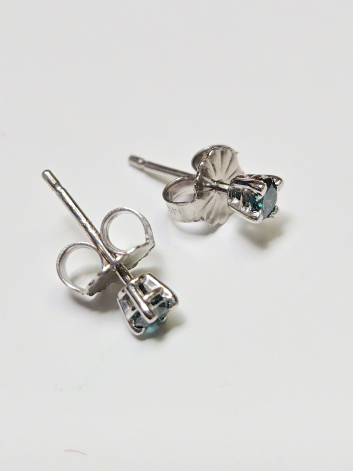 14K white gold stud earrings featuring 0.1ct round treated blue diamond, from Chique Jewelry.