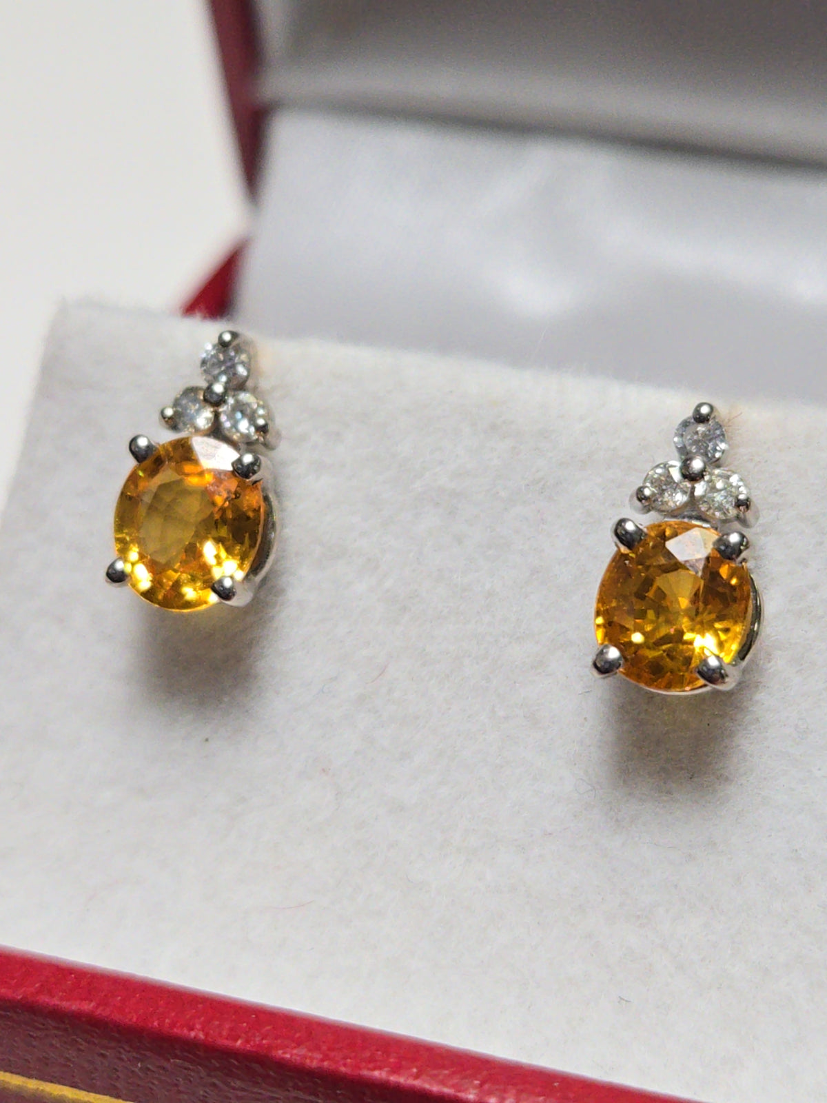 14K white gold stud earrings with 1.6ct oval orange sapphire, featuring elegant design and sparkling gemstone detail.