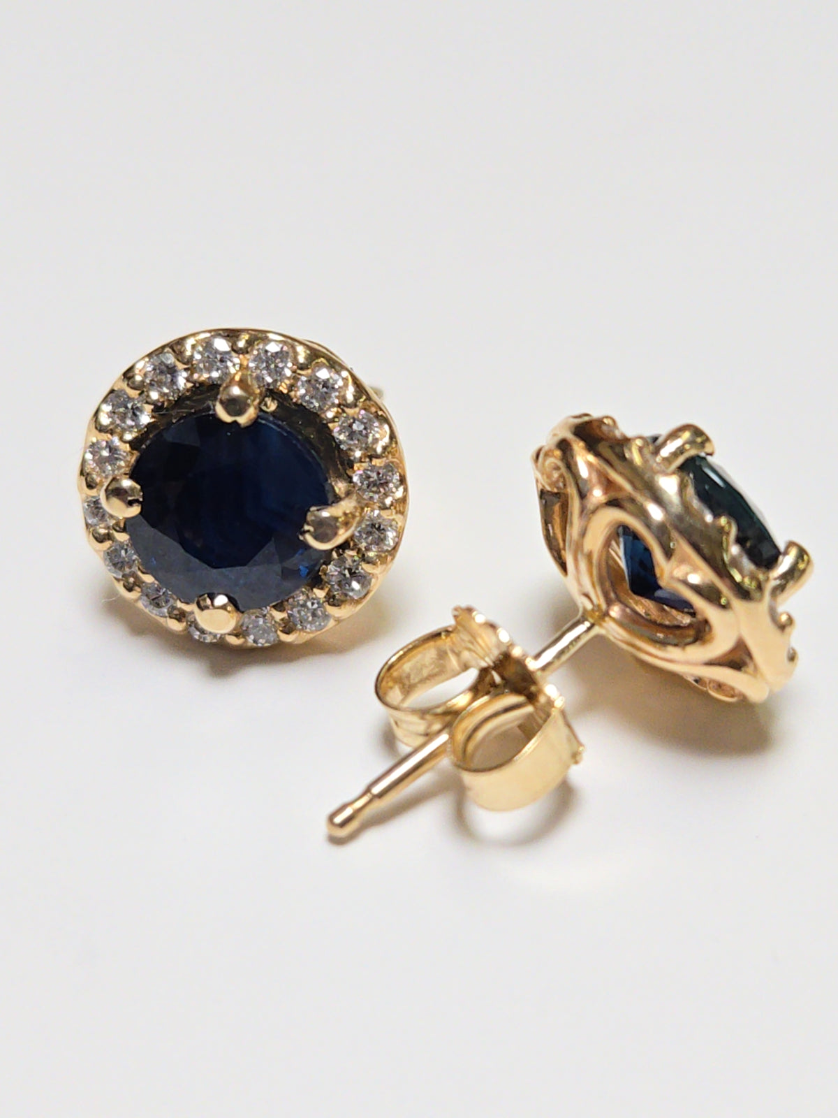 14K gold two-stone stud earrings with 2.45ct round blue sapphires, featuring elegant jewelry design and sparkling gemstones.