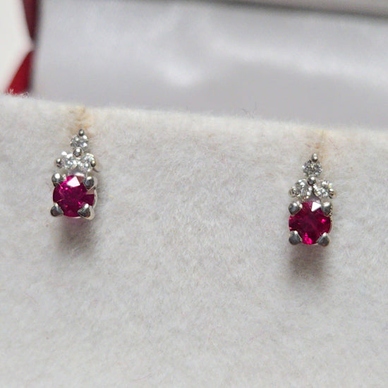 14K white gold stud earrings with 0.2ct round ruby, featuring a simple and elegant design from Chique Jewelry.