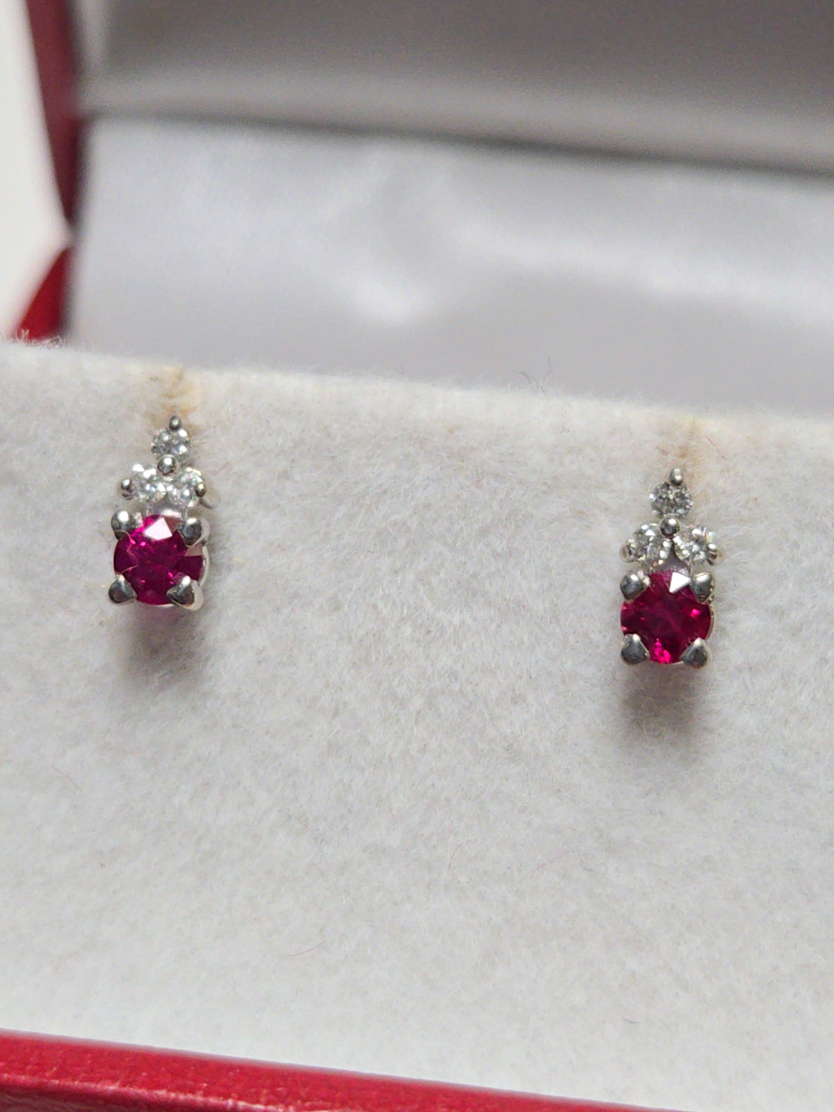 14K white gold stud earrings with 0.2ct round ruby, featuring a simple and elegant design from Chique Jewelry.