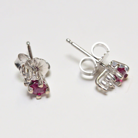 14K white gold stud earrings with 0.2ct round ruby, featuring a secure post and butterfly back, from Chique Jewelry