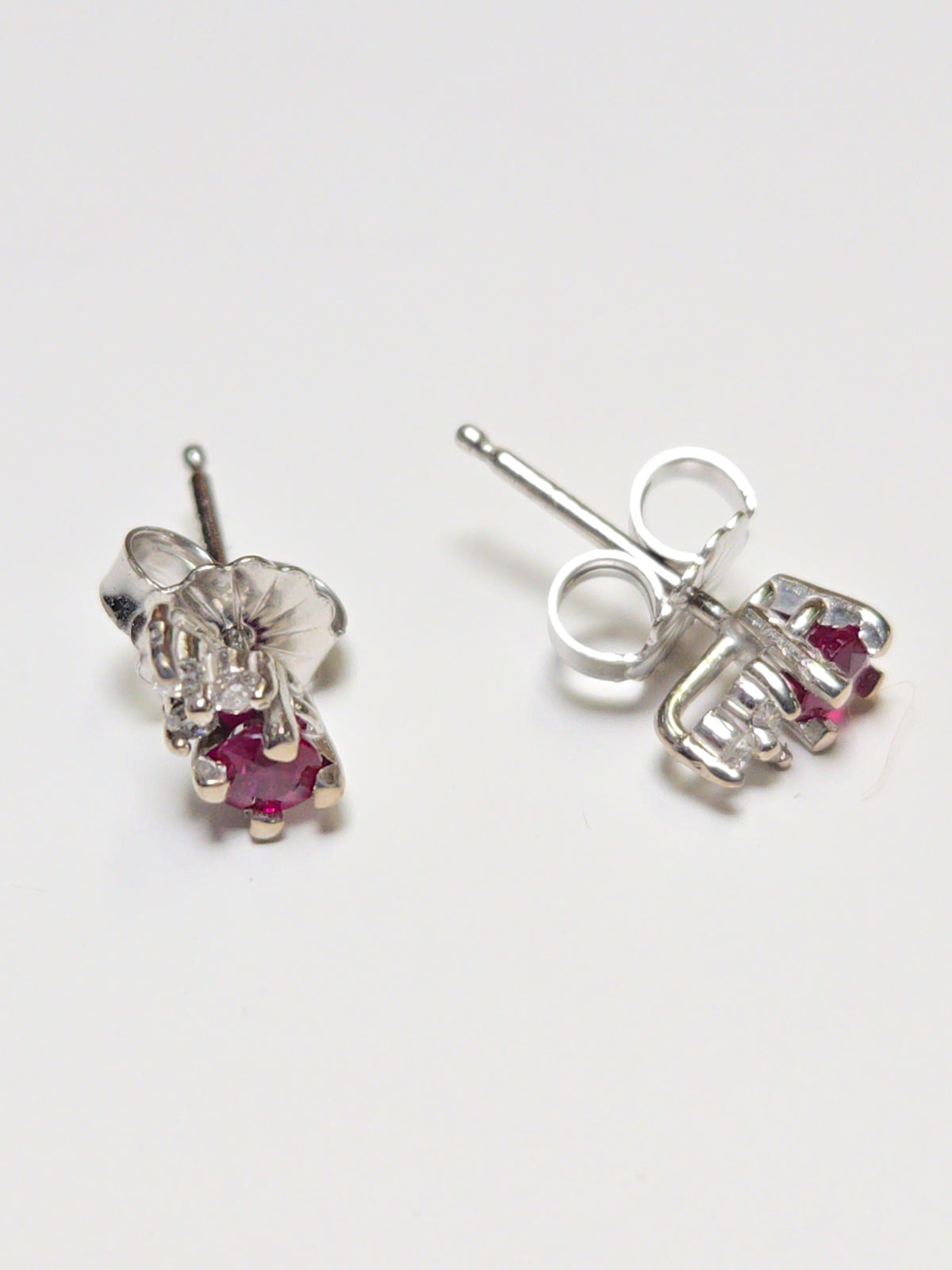 14K white gold stud earrings with 0.2ct round ruby, featuring a secure post and butterfly back, from Chique Jewelry